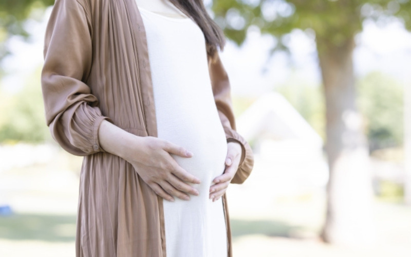 お腹に手を当てて立つ妊婦